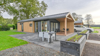 Lujosa cabaña con sauna en Drentse Weelde, Países Bajos, terraza exterior moderna y coche aparcado al lado.