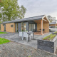 Moderne luksuslodge med sauna ved Drentse Weelde i Holland, udendørs terrasse og bil parkeret ved siden af.