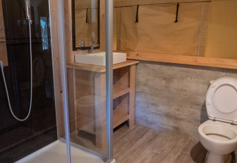 Badeværelse i safaritelt med bruser, håndvask og toilet på Camping La Colline i Belgien.