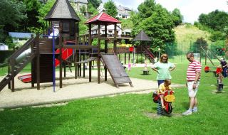 Spielplatz im Ferienpark Camping la Roche in Belgien mit Kindern, Eltern und vielfältigen Spielgeräten.