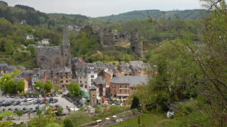 Vista de Camping la Roche en Limburgo, Bélgica, con iglesia, ruinas de castillo y colinas verdes.