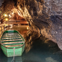 Un bote verde amarrado dentro de una cueva iluminada cerca de La Roche-en-Ardenne, Limburg, Bélgica.