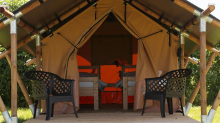 Tienda safari Duo Lodge en Camping de Boomgaard en Bélgica, con dos sillas plásticas en una tarima.