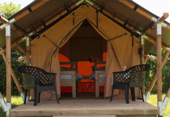 Tienda safari Duo Lodge en Camping de Boomgaard en Bélgica, con dos sillas plásticas en una tarima.