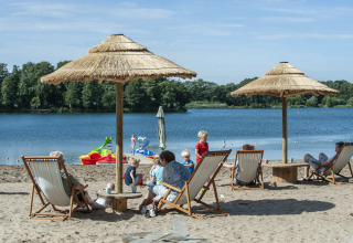 Vakantiepark Camping Sevink Molen in Gelderland, Nederland, met mensen op strandstoelen bij het meer.