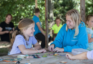 Bambini si divertono con attività creative al tavolo al Camping Sevink Molen, parco vacanze in Gelderland, Paesi Bassi.