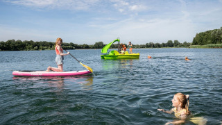Niños disfrutan de actividades acuáticas como paddle surf, barca a pedales y natación en Sevink Molen.