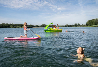 Bambini si divertono con sup, pedalò e nuoto nel lago di Camping Sevink Molen, in Gelderland, Paesi Bassi.
