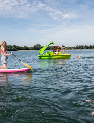 Niños disfrutan de actividades acuáticas como paddle surf, barca a pedales y natación en Sevink Molen.