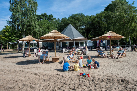 Familias descansan y niños juegan en la arena en Camping Sevink Molen, un parque vacacional en Gelderland.