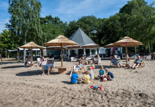 Familier slapper af og børn leger i sandet ved Camping Sevink Molen feriepark i Gelderland, Holland.