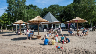 Familias descansan y niños juegan en la arena en Camping Sevink Molen, un parque vacacional en Gelderland.