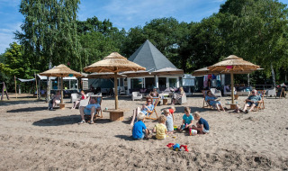 Familias descansan y niños juegan en la arena en Camping Sevink Molen, un parque vacacional en Gelderland.