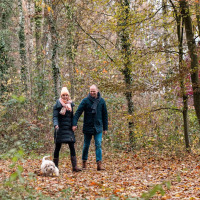 Pareja paseando con un perro pequeño por un bosque otoñal cerca de Winterswijk - Meddo, Gelderland, Países Bajos.