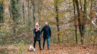 Pareja paseando con un perro pequeño por un bosque otoñal cerca de Winterswijk - Meddo, Gelderland, Países Bajos.
