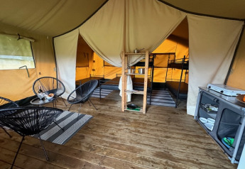 Inde i en safariteltsuite på Camping De La Vallée i Belgien med siddeområde, køkken og køjesenge.