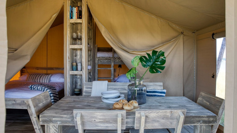 Interior de una tienda safari en Camping Sevink Molen, Países Bajos, con muebles rústicos y camas.