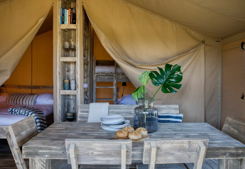 Interior de una tienda safari en Camping Sevink Molen, Países Bajos, con muebles rústicos y camas.