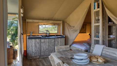 Interior de la tienda Safari Mill en Camping Sevink Molen en Países Bajos, con muebles de madera y ambiente acogedor.
