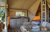 Interior de la tienda Safari Mill en Camping Sevink Molen en Países Bajos, con muebles de madera y ambiente acogedor.