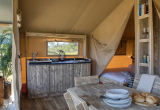 Intérieur de la tente Safari Mill au Camping Sevink Molen aux Pays-Bas, avec meubles en bois et décor chaleureux.