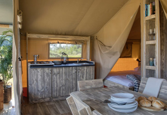 Interior de la tienda Safari Mill en Camping Sevink Molen en Países Bajos, con muebles de madera y ambiente acogedor.