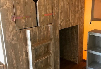 Interno di tenda safari con scala di legno e porta con intaglio a cuore presso Camping Sevink Molen, Paesi Bassi.