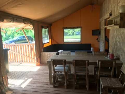 Vista interna della tenda Safari Hilgelo al Camping Sevink Molen nei Paesi Bassi, con area pranzo e salotto.