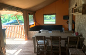 Vista interior de la tienda Safari Hilgelo en Camping Sevink Molen, Países Bajos, con comedor y zona de estar.