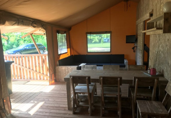 Vista interna della tenda Safari Hilgelo al Camping Sevink Molen nei Paesi Bassi, con area pranzo e salotto.