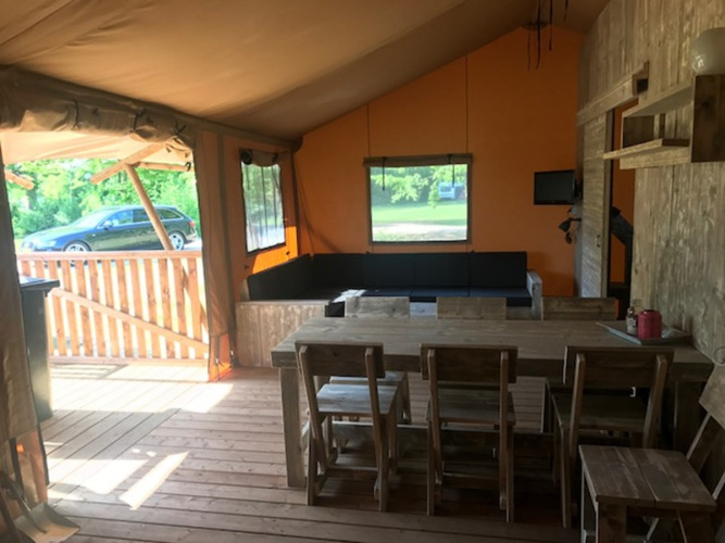 Vista interior de la tienda Safari Hilgelo en Camping Sevink Molen, Países Bajos, con comedor y zona de estar.