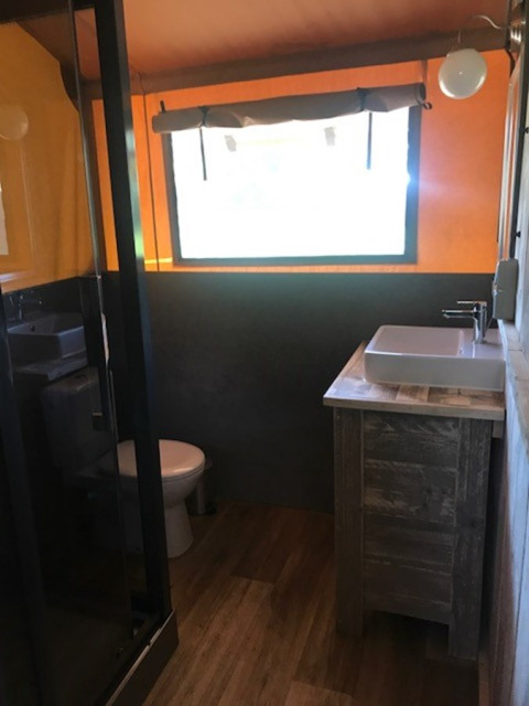 Baño moderno en la tienda Safari Hilgelo en Camping Sevink Molen, Países Bajos, con detalles en madera.