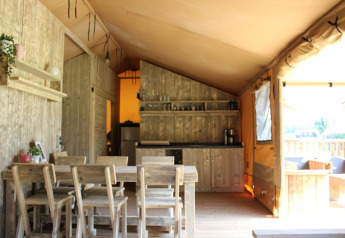 Innenansicht des Safari-Zelts Hilgelo auf Camping Sevink Molen, mit Holzmöbeln und Küchenbereich.