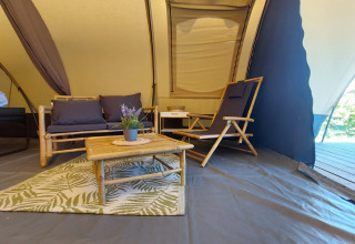 Interior de la tienda Tunnel tent Sevink en Camping Sevink Molen, Países Bajos, con muebles de bambú.