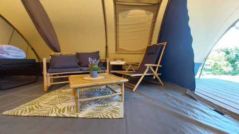 Interior de la tienda Tunnel tent Sevink en Camping Sevink Molen, Países Bajos, con muebles de bambú.