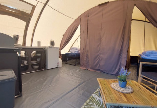 Interior de la Tunnel tent Sevink en Camping Sevink Molen con camas, sofá, cocina y decoración.