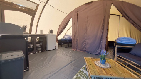 Interior of Tunnel tent Sevink at Camping Sevink Molen with beds, sofa, kitchenette and decor.