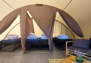 Inde i Tunnel-teltet Sevink på Camping Sevink Molen i Holland, med fire opredte senge og loungemøbler.