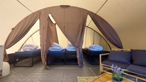 Interior de la tienda Tunnel Sevink en Camping Sevink Molen, Países Bajos, con camas y zona de descanso.