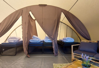 Inde i Tunnel-teltet Sevink på Camping Sevink Molen i Holland, med fire opredte senge og loungemøbler.