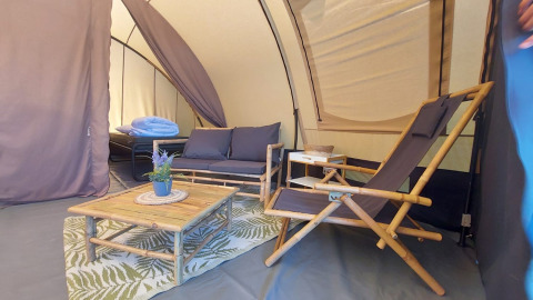 Interior de la tienda Tunnel Sevink con muebles de bambú en Camping Sevink Molen, Países Bajos.