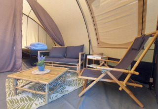 Interior de la tienda Tunnel Sevink con muebles de bambú en Camping Sevink Molen, Países Bajos.