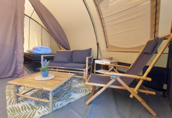 Indretning i Tunnel tent Sevink med bambusmøbler og komfortabel lounge på Camping Sevink Molen, Holland.