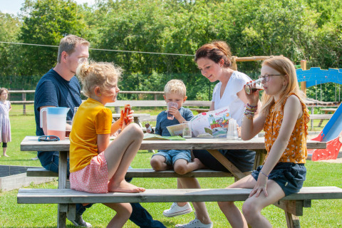 Familia disfrutando de un picnic en una mesa de madera en Camping Sevink Molen, Gelderland, Países Bajos.