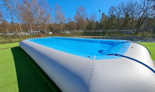 Inflatable swimming pool at Camping Het Veen holiday park in Antwerp, Belgium, surrounded by trees.