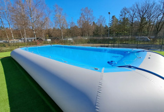 Piscina gonfiabile al Camping Het Veen, un villaggio turistico ad Anversa, Belgio, con alberi attorno.