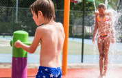 Bambini che si divertono nell’area giochi d’acqua al sole al Camping Het Veen, parco vacanze ad Anversa, Belgio.
