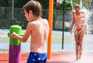 Niños juegan en una zona de juegos acuáticos bajo el sol en Camping Het Veen, parque vacacional en Amberes, Bélgica.
