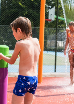 Niños juegan en una zona de juegos acuáticos bajo el sol en Camping Het Veen, parque vacacional en Amberes, Bélgica.