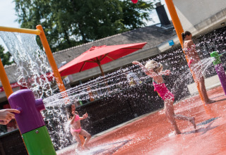 Bambini che giocano nell’area giochi d’acqua colorata al Camping Het Veen, Anversa, Belgio, d’estate.